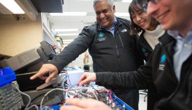 man and two students looking at electronics
