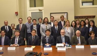 group of men and women sit and stand behind table