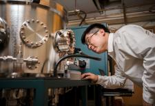 MIT Associate Professor Luqiao Liu utilizes novel materials and electron spin to create next-generation memory hardware for computers that can store more information, use less power to operate, and retain information for a longer period of time. In this photo, Liu peers inside a sputtering deposition system, which is used to grow magnetic thin films.