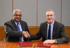 men shake hands sitting behind table