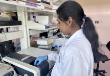 Women in white lab coat stands in front of machine