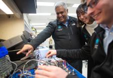 man and two students looking at electronics